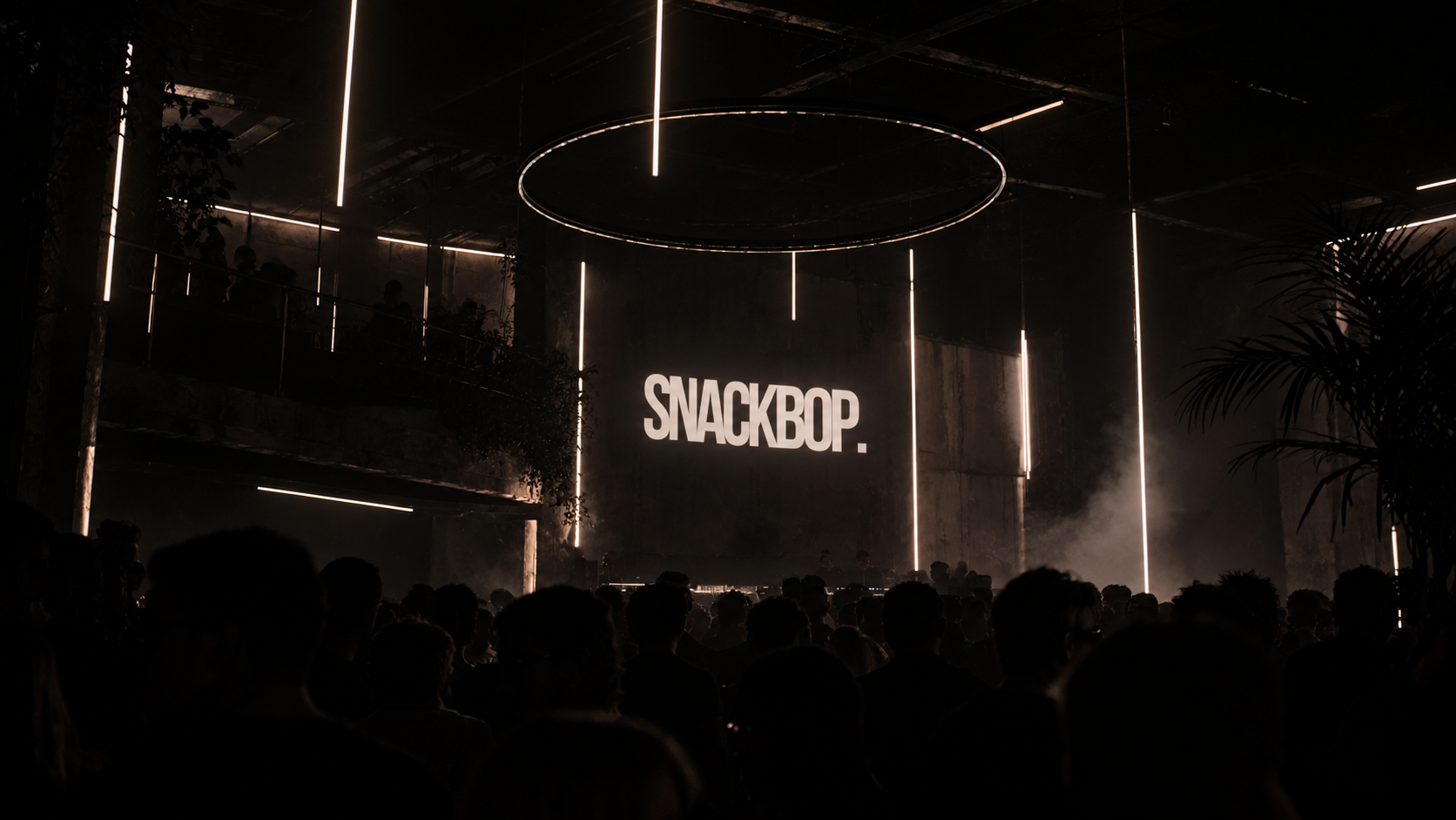 A packed industrial club lit by warm amber lights